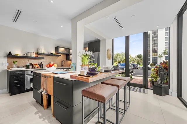 a kitchen with a stove a sink a refrigerator and chairs