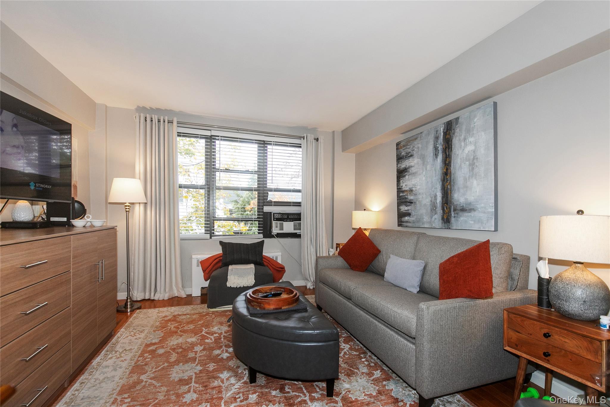 15 Canterbury Road, Unit D6 Great Neck, NY 11021 - Photo 8 of 21 a living room with furniture a large window and a flat screen tv