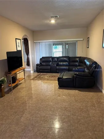 a living room with furniture a flat screen tv and kitchen view