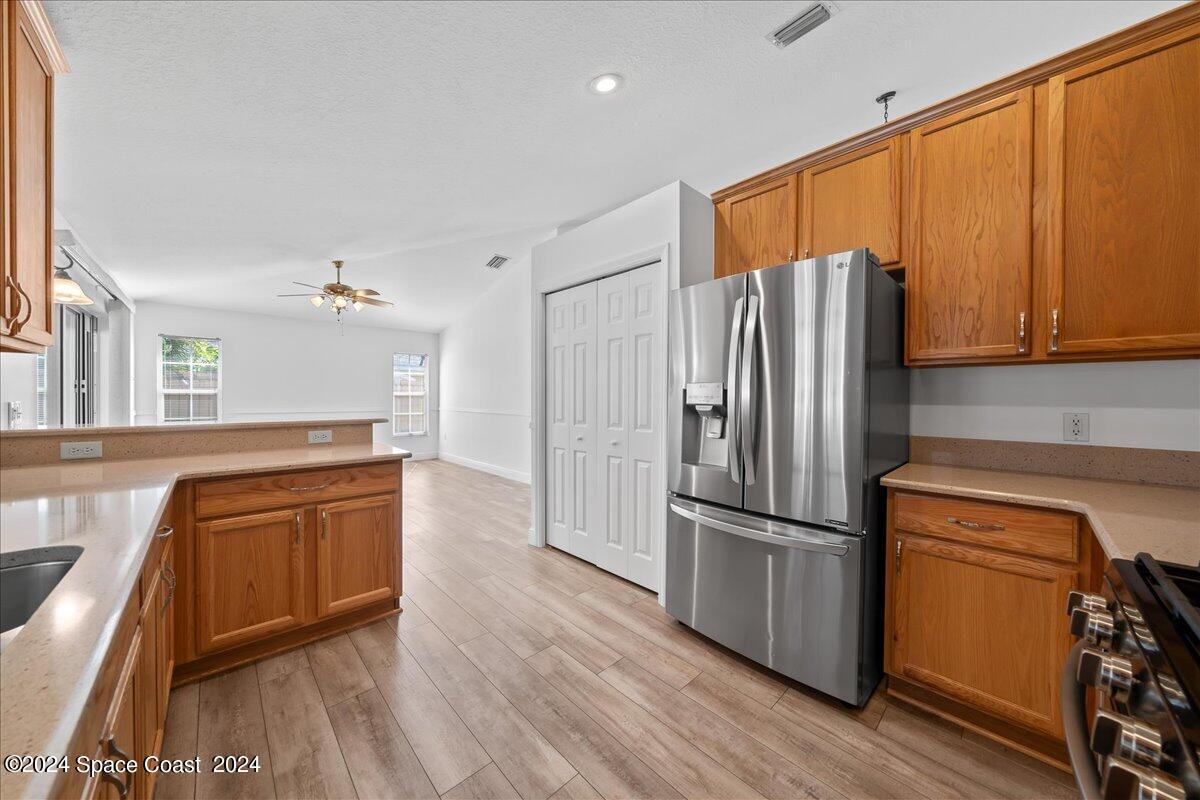 432 Stonehenge Circle Rockledge, FL 32955 - Photo 12 of 41 a kitchen with stainless steel appliances granite countertop a refrigerator a sink dishwasher and wooden cabinets with wooden floor
