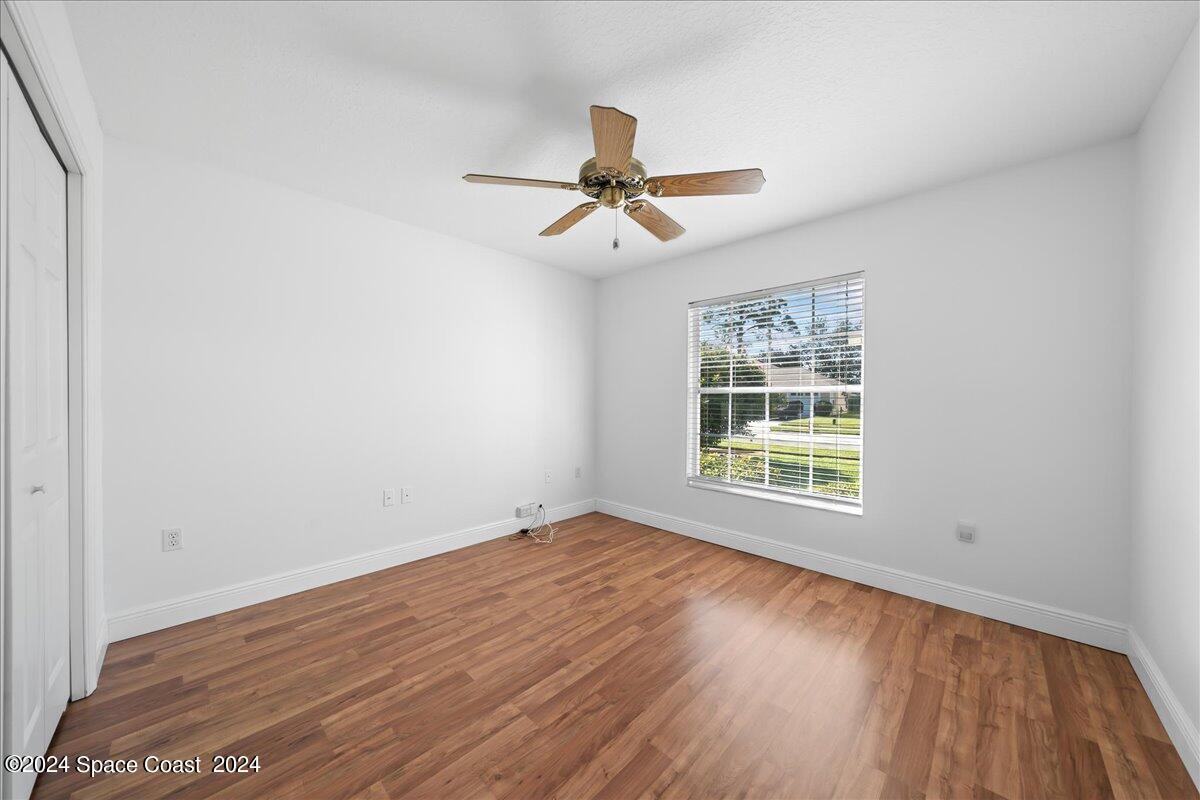 432 Stonehenge Circle Rockledge, FL 32955 - Photo 25 of 41 an empty room with wooden floor ceiling fan and windows