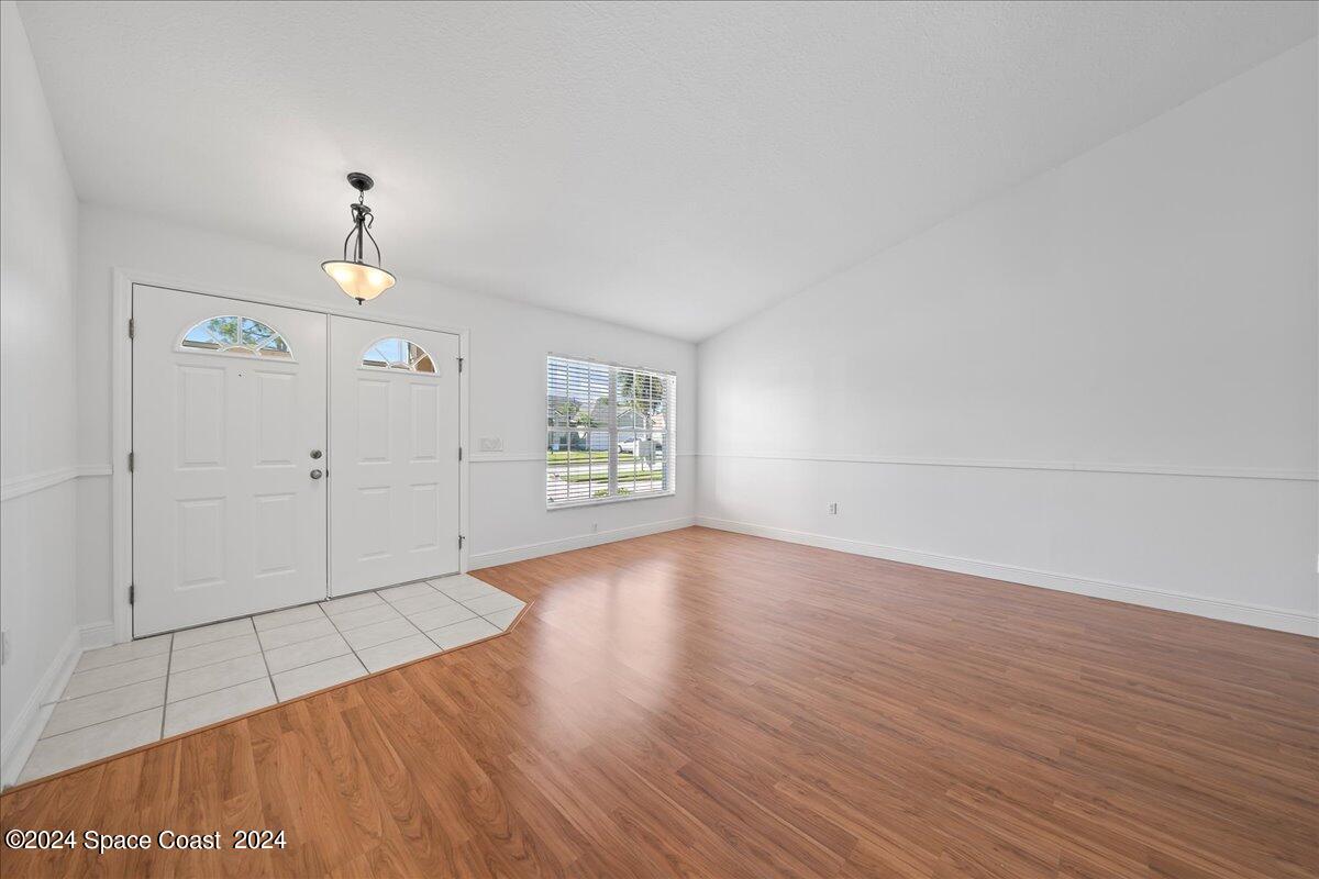 432 Stonehenge Circle Rockledge, FL 32955 - Photo 9 of 41 an empty room with wooden floor chandelier and windows