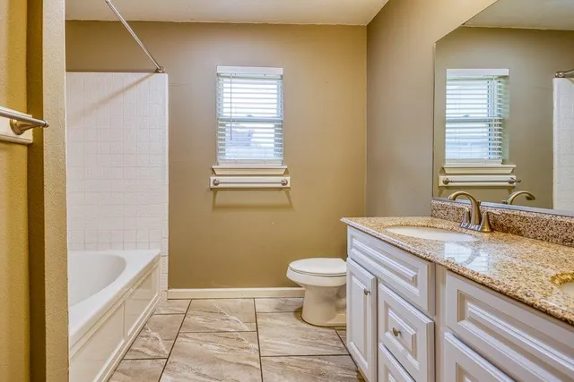 a bathroom with a granite countertop sink toilet and bathtub