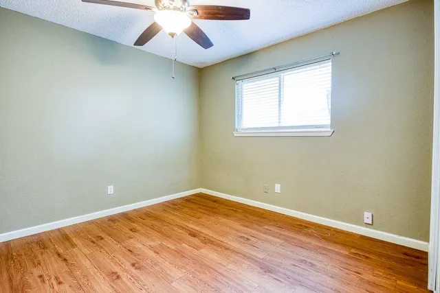 a view of empty room with wooden floor and fan