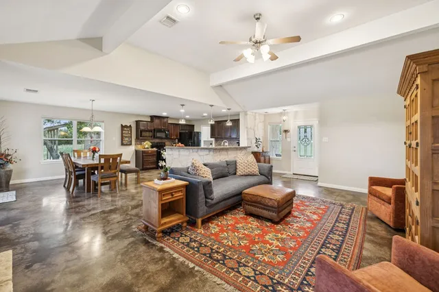 a living room with furniture kitchen view and a chandelier