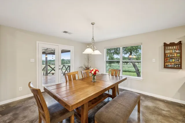 a dining room with wooden floor a chandelier a wooden table and chairs