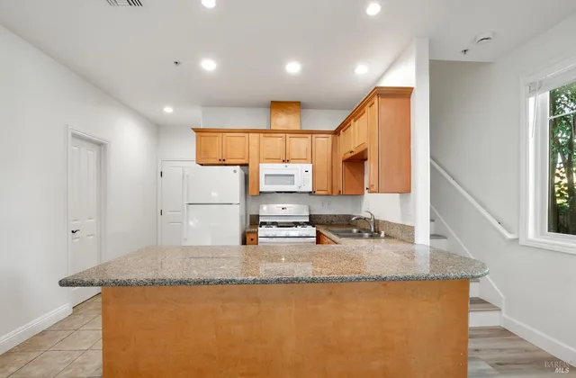 a kitchen with stainless steel appliances granite countertop a sink a stove and a refrigerator