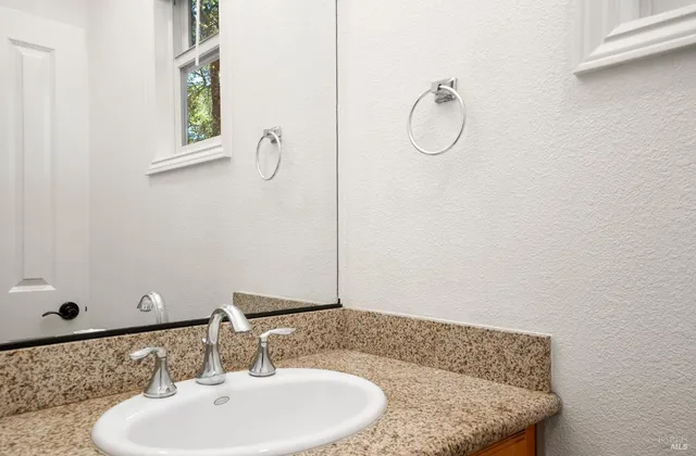 a bathroom with a granite countertop sink and a mirror