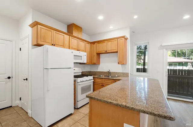 a kitchen with granite countertop a refrigerator a stove a sink a counter top space and cabinets