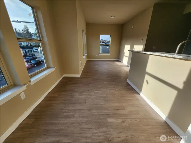 a view of a hallway with wooden floor and a living room
