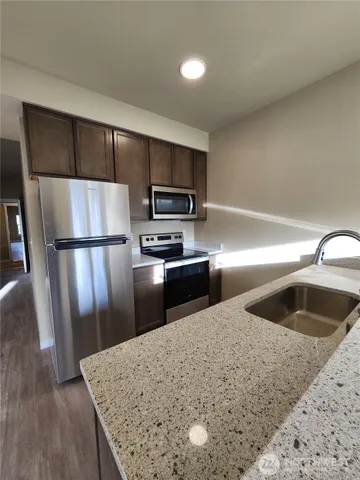 a kitchen with granite countertop a refrigerator and a sink