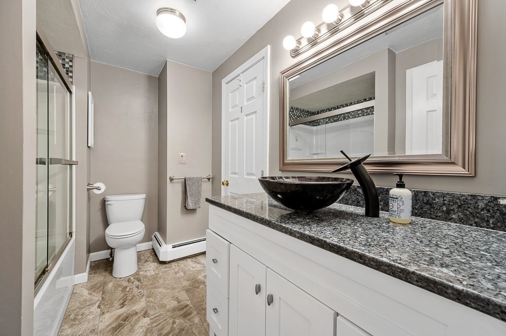 4 Tuck Farm Road, Unit 6 Auburn, MA 01501 - Photo 16 of 20 a bathroom with a granite countertop toilet a sink and a mirror