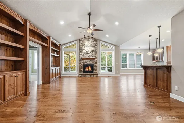 a view of an empty room with wooden floor fireplace and a window
