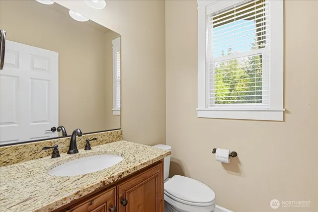 a bathroom with a granite countertop sink toilet and mirror