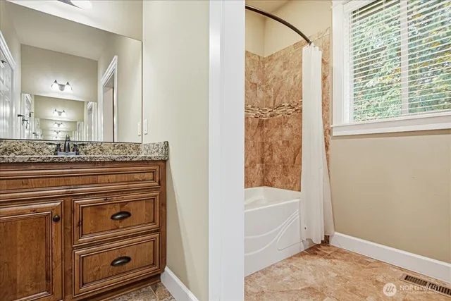 a bathroom with a granite countertop sink a mirror and shower