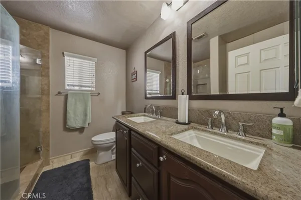 a bathroom with a granite countertop sink a toilet a mirror and shower