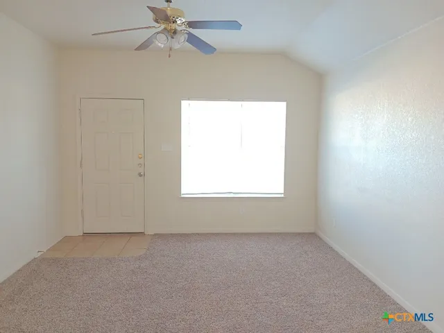 an empty room with a window and a fan