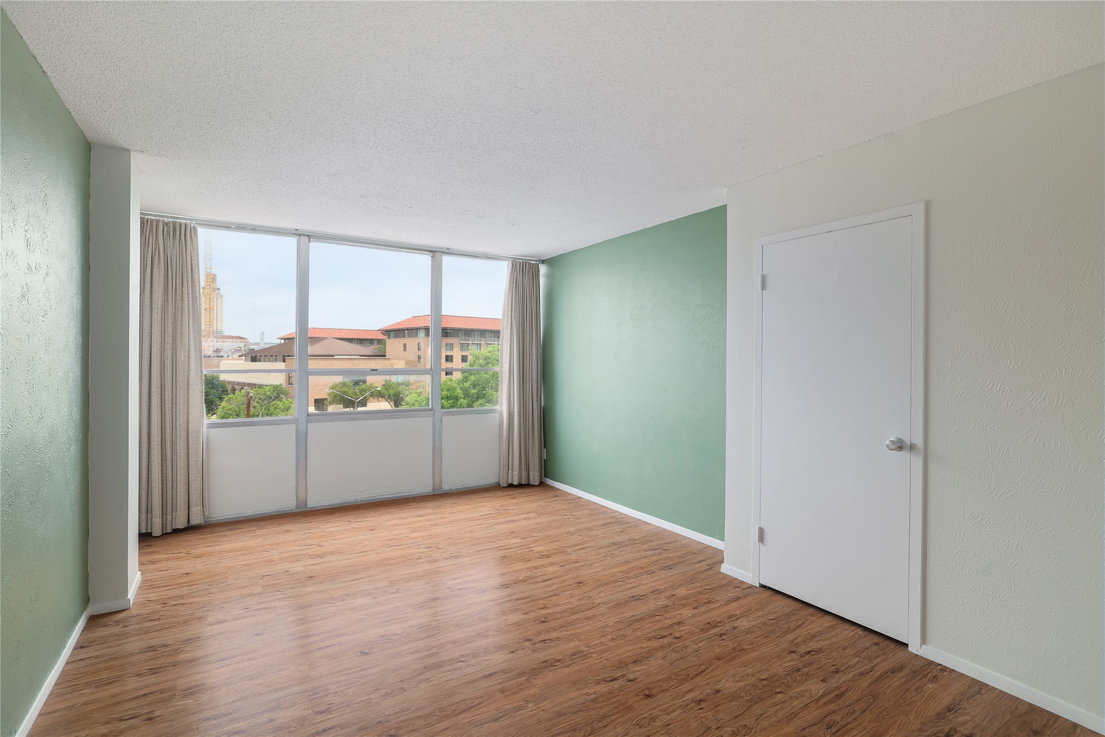 1800 Lavaca Street, Unit A508 Austin, TX 78701 - Photo 21 of 25 The property features expansive windows with views of architectural buildings and trees, and walls painted in a combination of green and light neutral tones