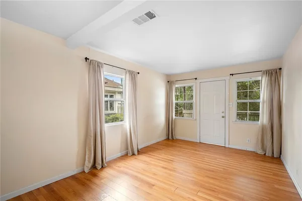 an empty room with wooden floor and windows