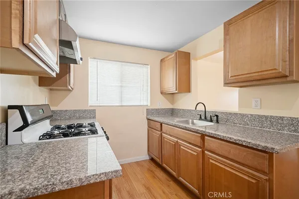 a kitchen with granite countertop a sink a stove and cabinets