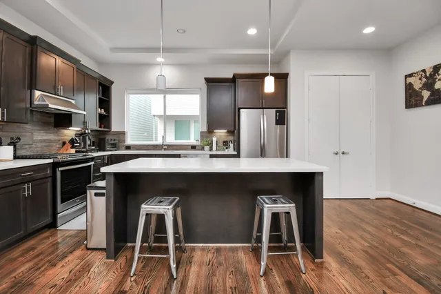 a kitchen with kitchen island granite countertop a stove a sink and a refrigerator with wooden floor