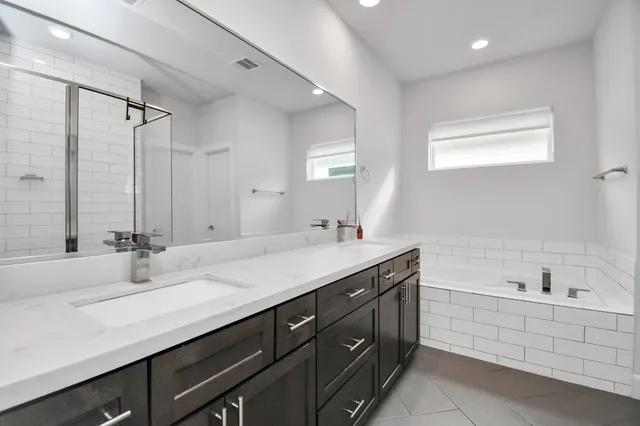 a bathroom with a double vanity sink mirror double and bathtub