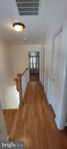 a view of a hallway with wooden floor and cabinet