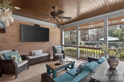 a living room with furniture a flat screen tv and a floor to ceiling window
