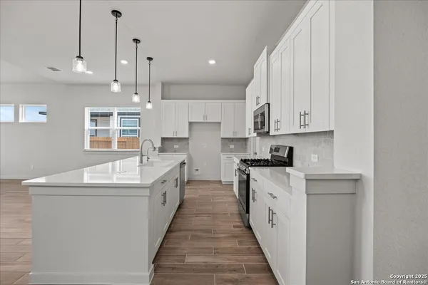 a large white kitchen with stainless steel appliances granite countertop a sink and dishwasher a stove with wooden floor