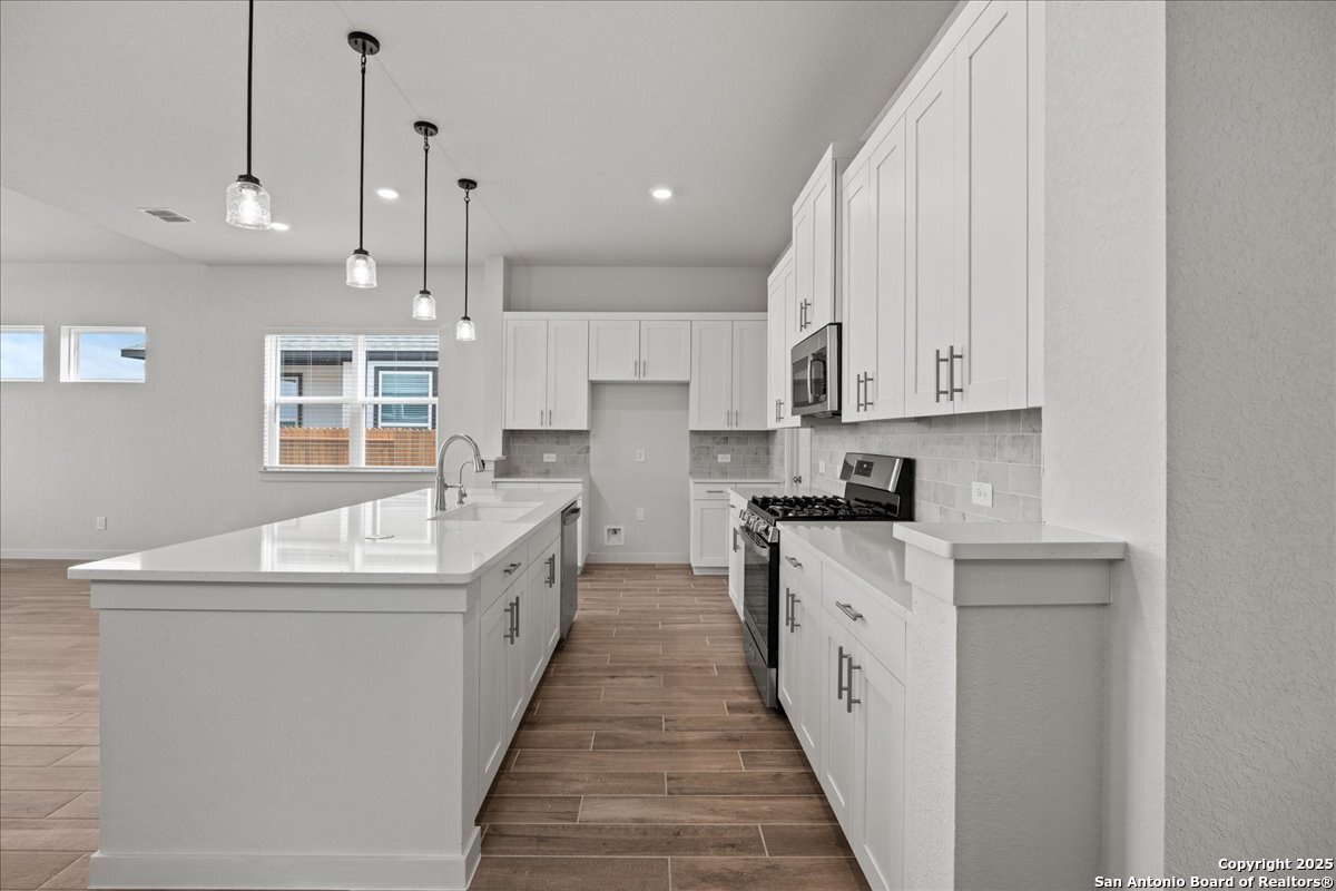 2130 Shepards Street Seguin, TX 78155 - Photo 6 of 21 a large white kitchen with stainless steel appliances granite countertop a sink and dishwasher a stove with wooden floor