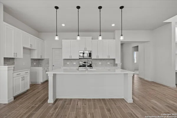 a large kitchen with kitchen island a stove a sink a center island and wooden floor