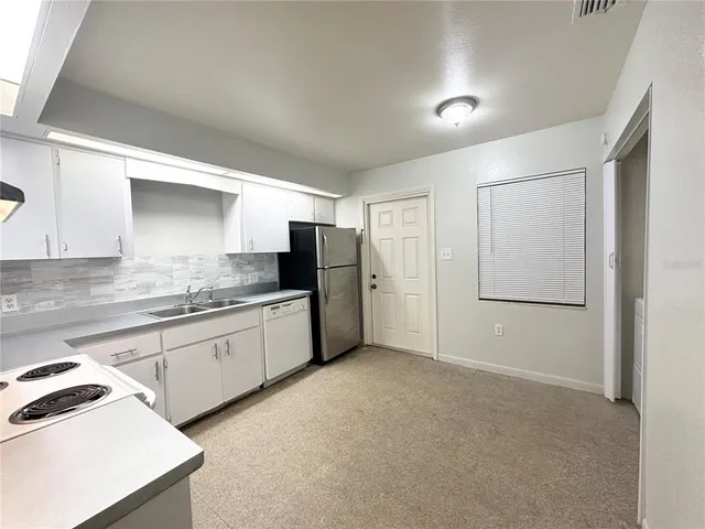 a kitchen with granite countertop white cabinets and refrigerator