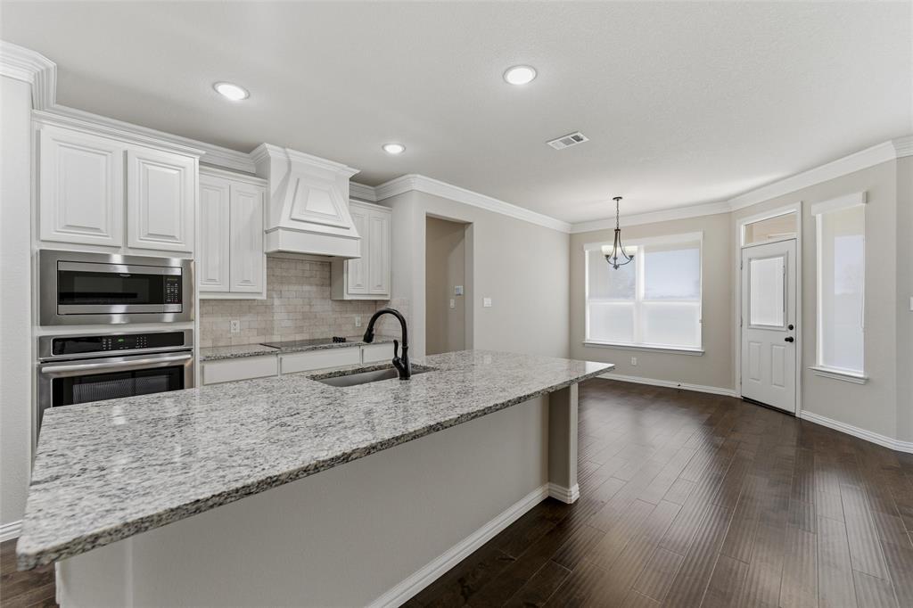 7437 Aniston Way Godley, TX 76044 - Photo 11 of 23 a kitchen with stainless steel appliances granite countertop a sink a stove and a microwave