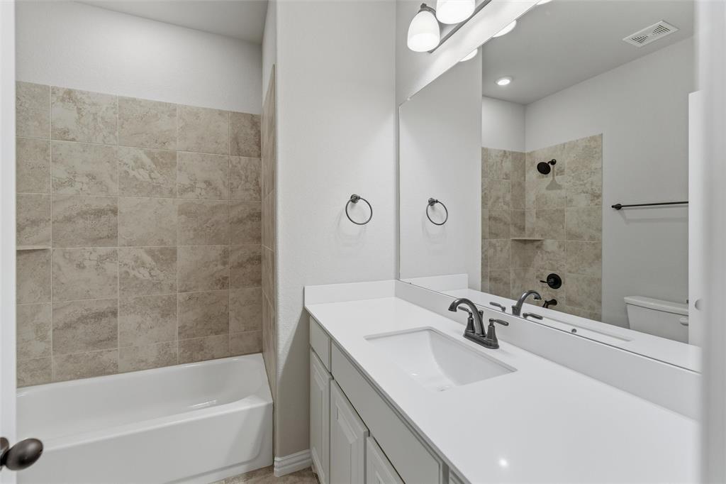 7437 Aniston Way Godley, TX 76044 - Photo 12 of 23 a bathroom with a sink a mirror and a bathtub