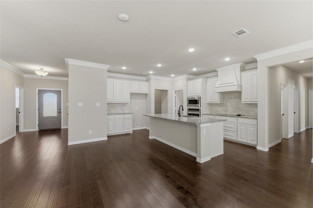 7437 Aniston Way Godley, TX 76044 - Photo 8 of 23 a open kitchen with white cabinets stainless steel appliances and wooden floor