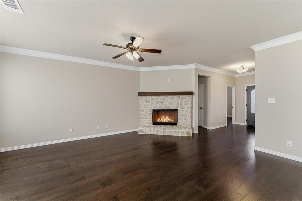 7437 Aniston Way Godley, TX 76044 - Photo 10 of 23 a view of an empty room with wooden floor and a fireplace