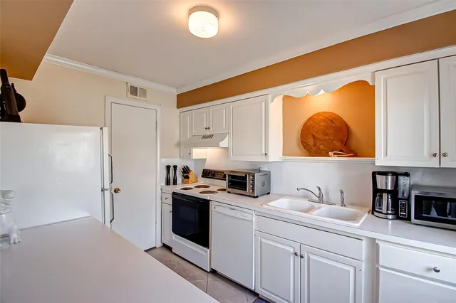 a kitchen with stainless steel appliances a sink a stove and white cabinets
