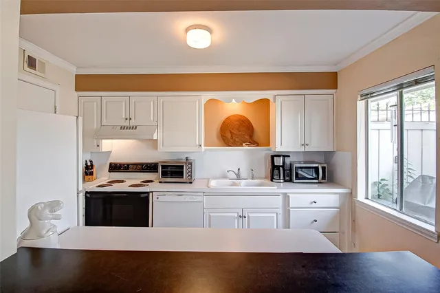 a kitchen with stainless steel appliances a sink a stove a microwave a counter top space and cabinets