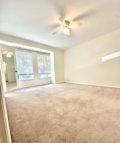 an empty room with chandelier fan and windows
