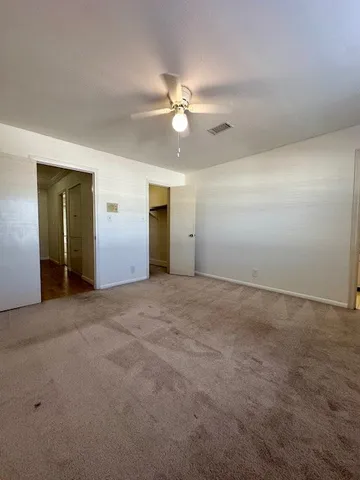 an empty room with closet and a ceiling fan