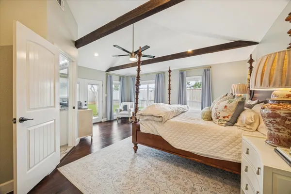 a bedroom with a bed ceiling fan and a wooden floor