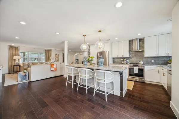 a kitchen with stainless steel appliances kitchen island wooden floors and white cabinets