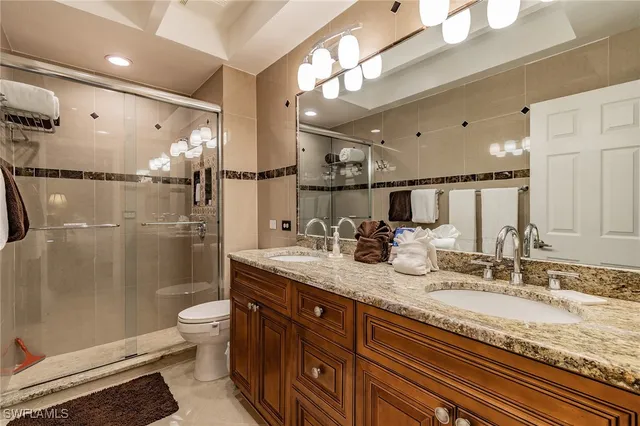 a bathroom with a granite countertop sink a toilet a mirror and shower