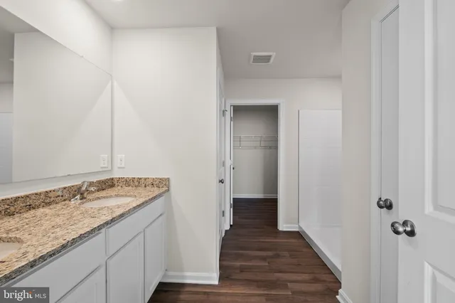 a bathroom with a granite countertop sink and a wooden floor