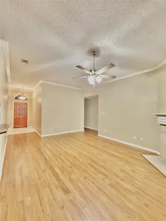 an empty room with wooden floor fan and windows