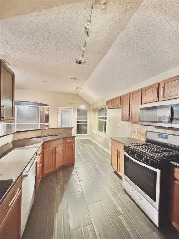 4005 Ridge Rock Drive Plano, TX 75074 - Photo 5 of 13 a large kitchen with stainless steel appliances granite countertop a stove and a sink