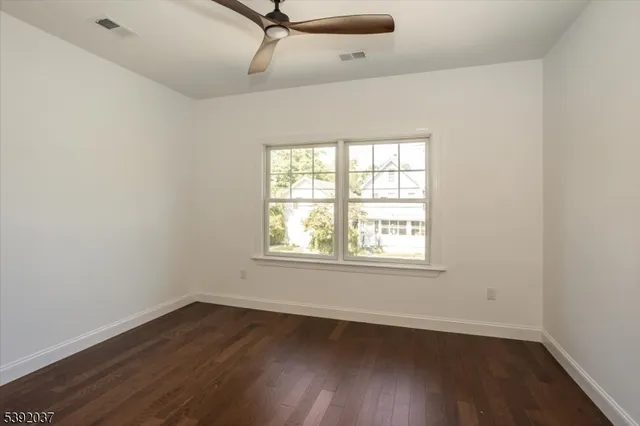 an empty room with wooden floor a ceiling fan and a window
