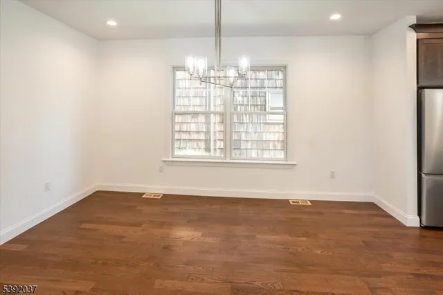 an empty room with chandelier fan and windows