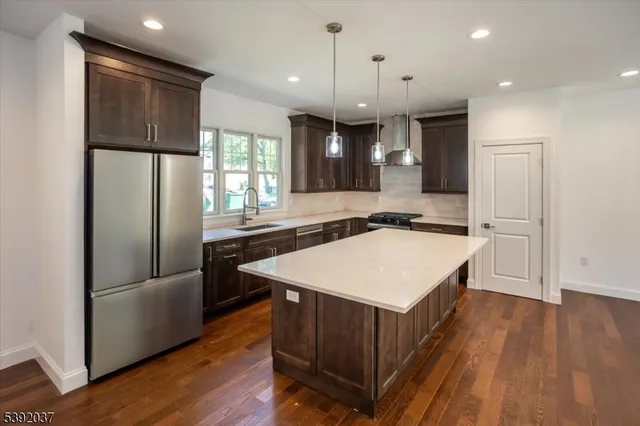 a kitchen with kitchen island a refrigerator a stove a sink and a oven with wooden floor