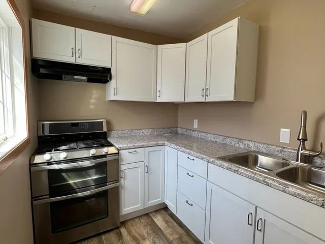 a kitchen with granite countertop white cabinets and stainless steel appliances